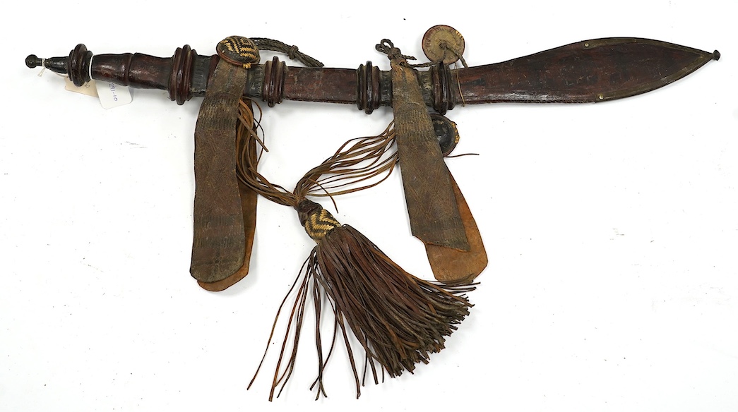 A late 19th century Nigerian Taboura from the Hausa People of Northern Nigeria, in leather scabbard, blade 59.5cm. Condition - good